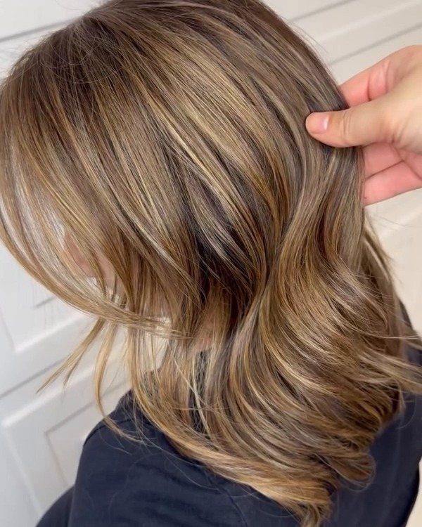 Layered light brown hair with cool ash-blonde highlights and darker roots