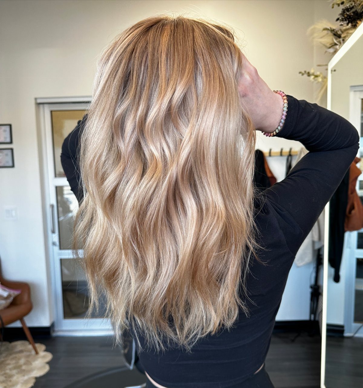 Long wavy blonde hair with warm honey highlights and darker roots
