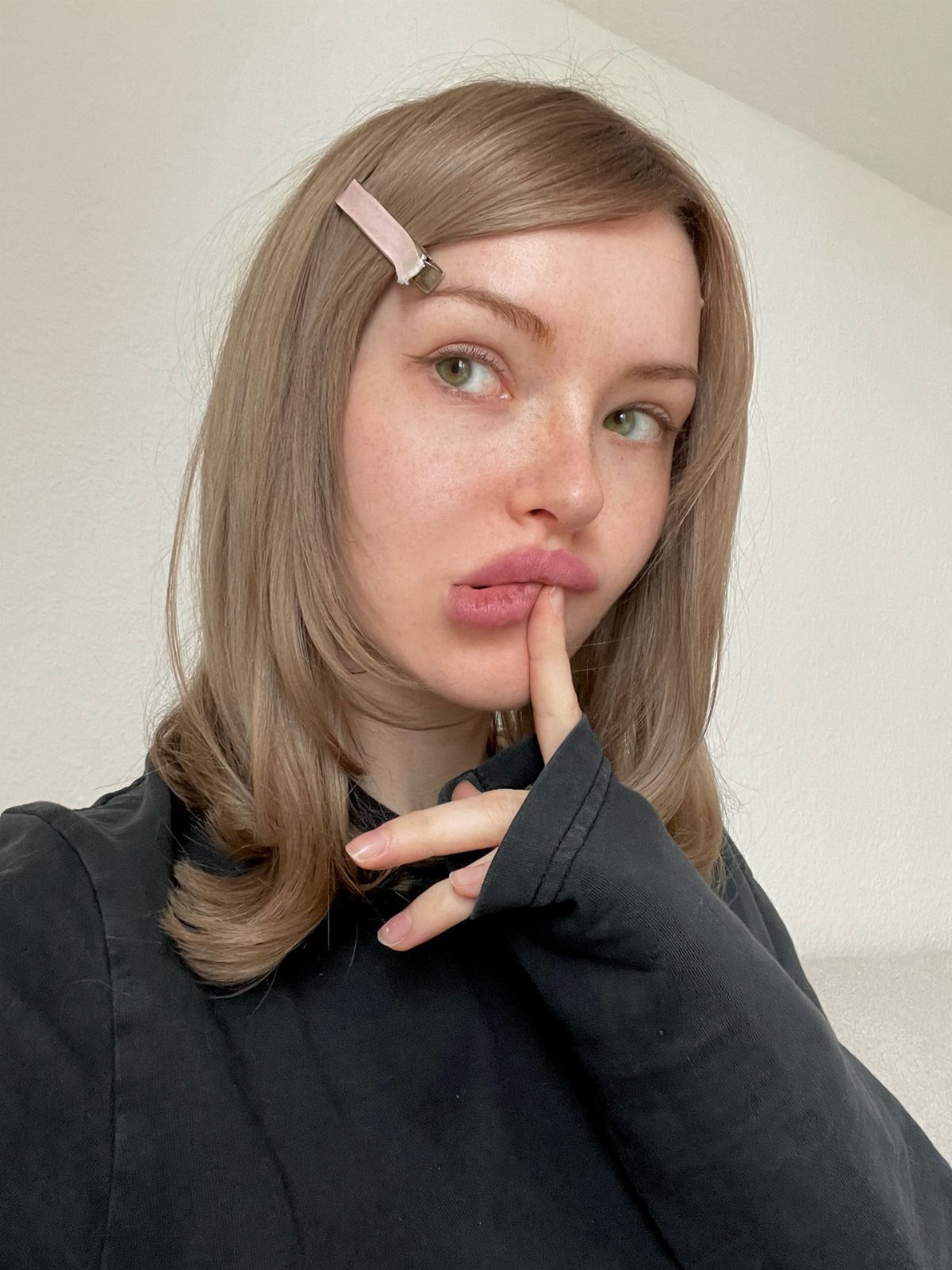 Woman with muted dark ash blonde hair and a pink hair clip