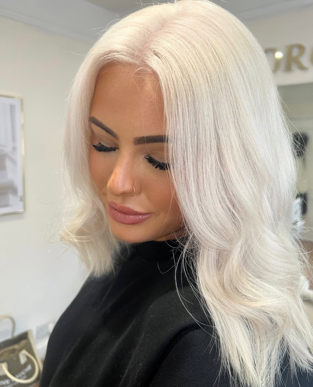 Woman with pale silvery ash blonde hair styled in loose waves at a salon