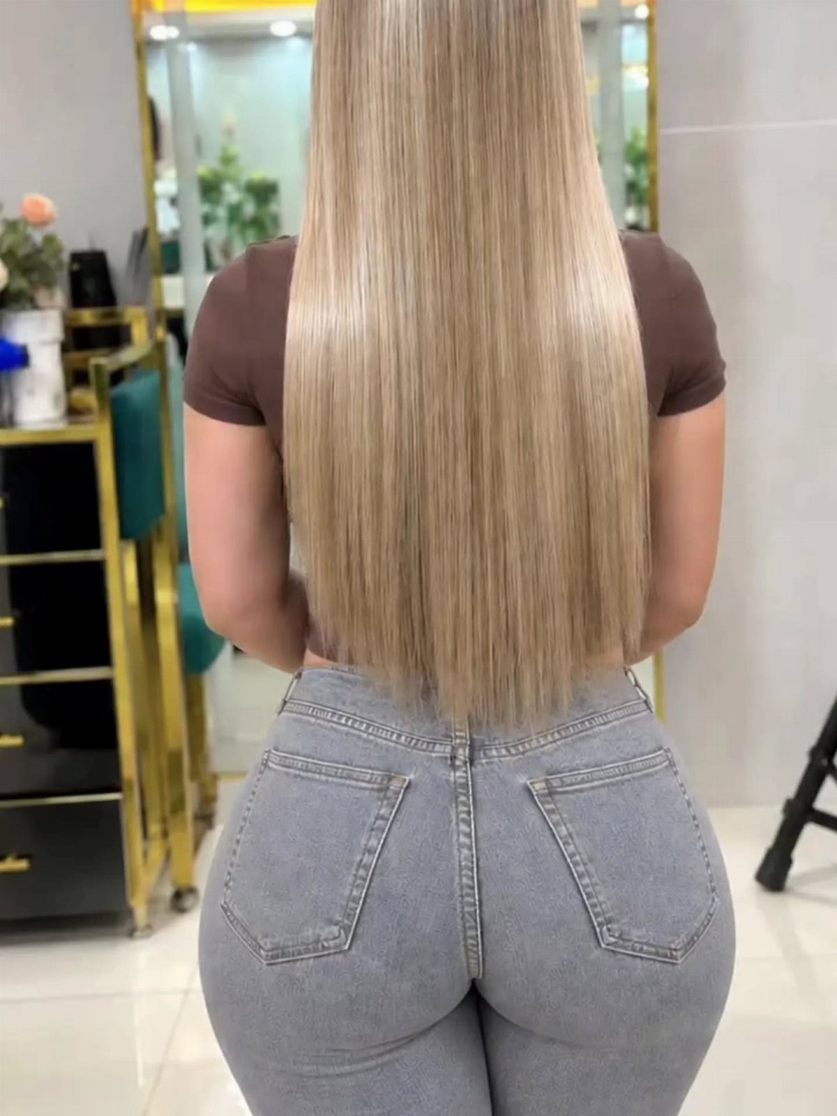 Long muted beige-blonde hair shown from behind in a salon.
