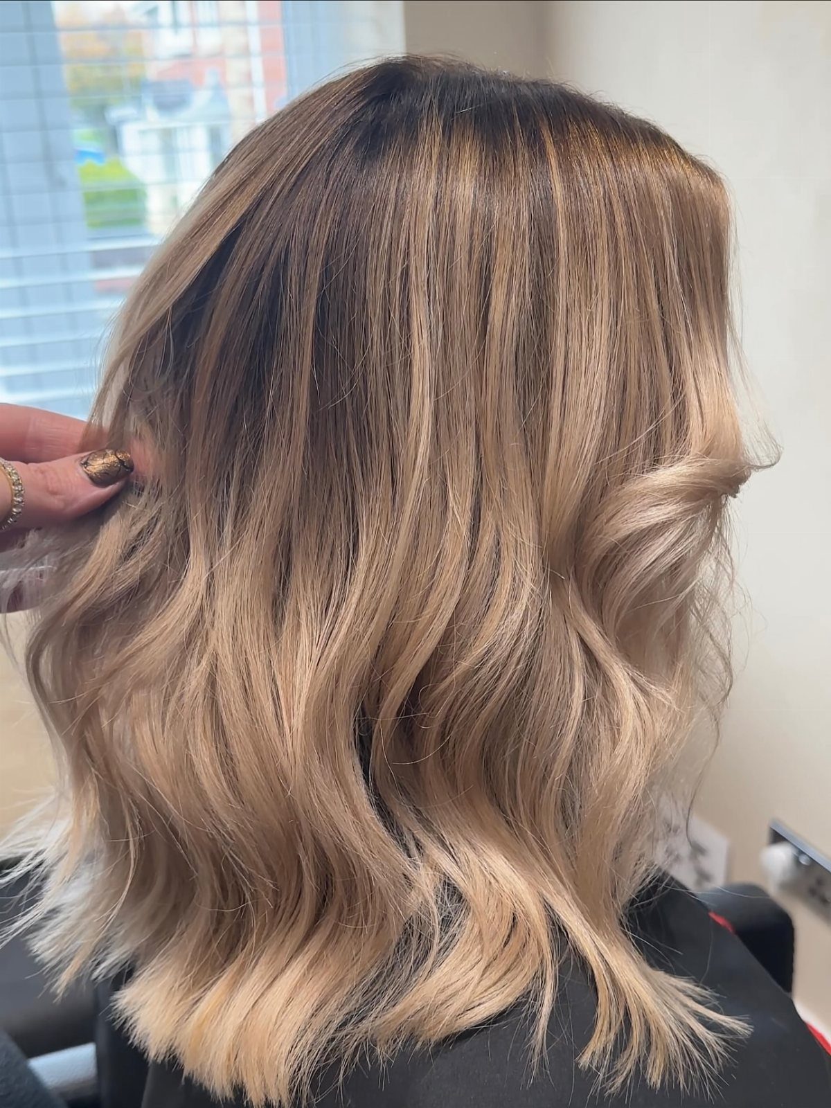 Wavy sandy taupe blonde hair with darker roots and softly lighter ends