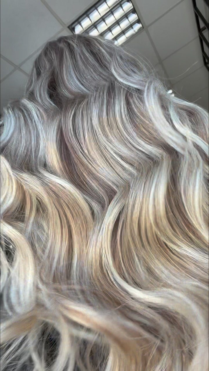 Wavy platinum ash blonde hair with cool silver tones and darker roots