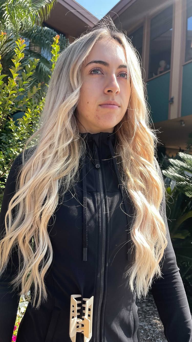 Woman with long wavy ash blonde hair and darker blended roots outdoors