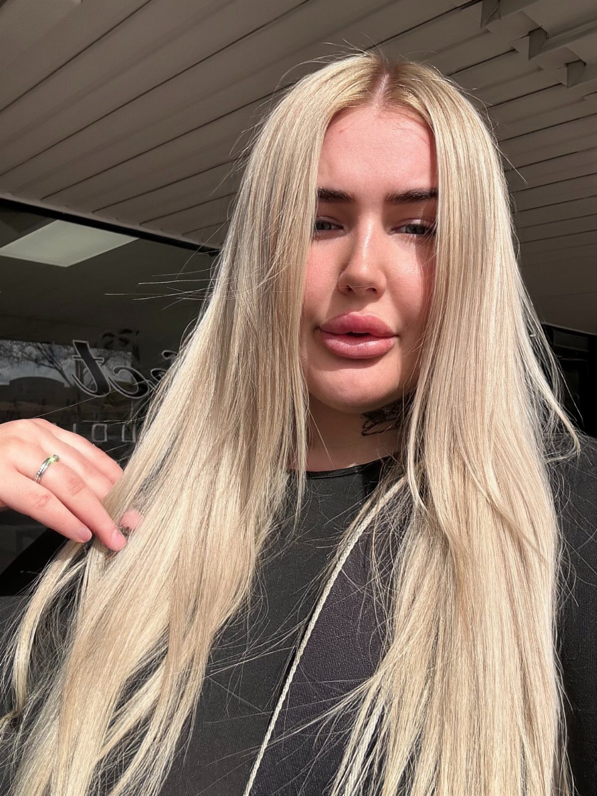 Long near-white ash blonde hair with darker roots frames a person’s face.