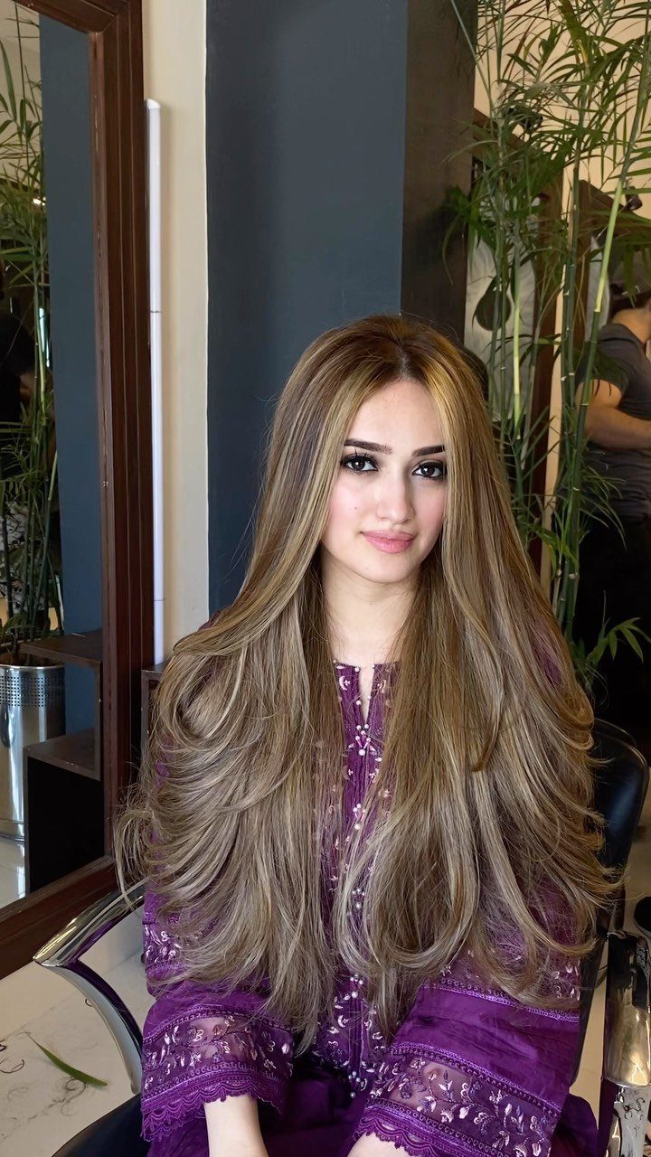 Woman with long light brown hair and pale blonde highlights seated in a salon