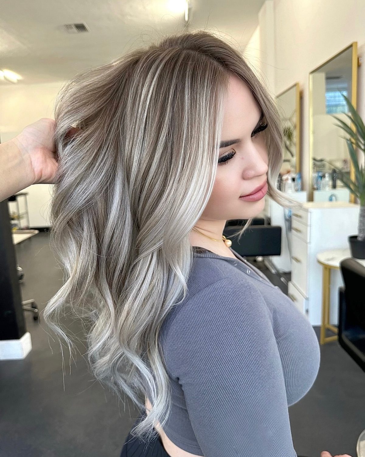 Woman showing cool ash-blonde ombre hair with dark roots and curled pale ends