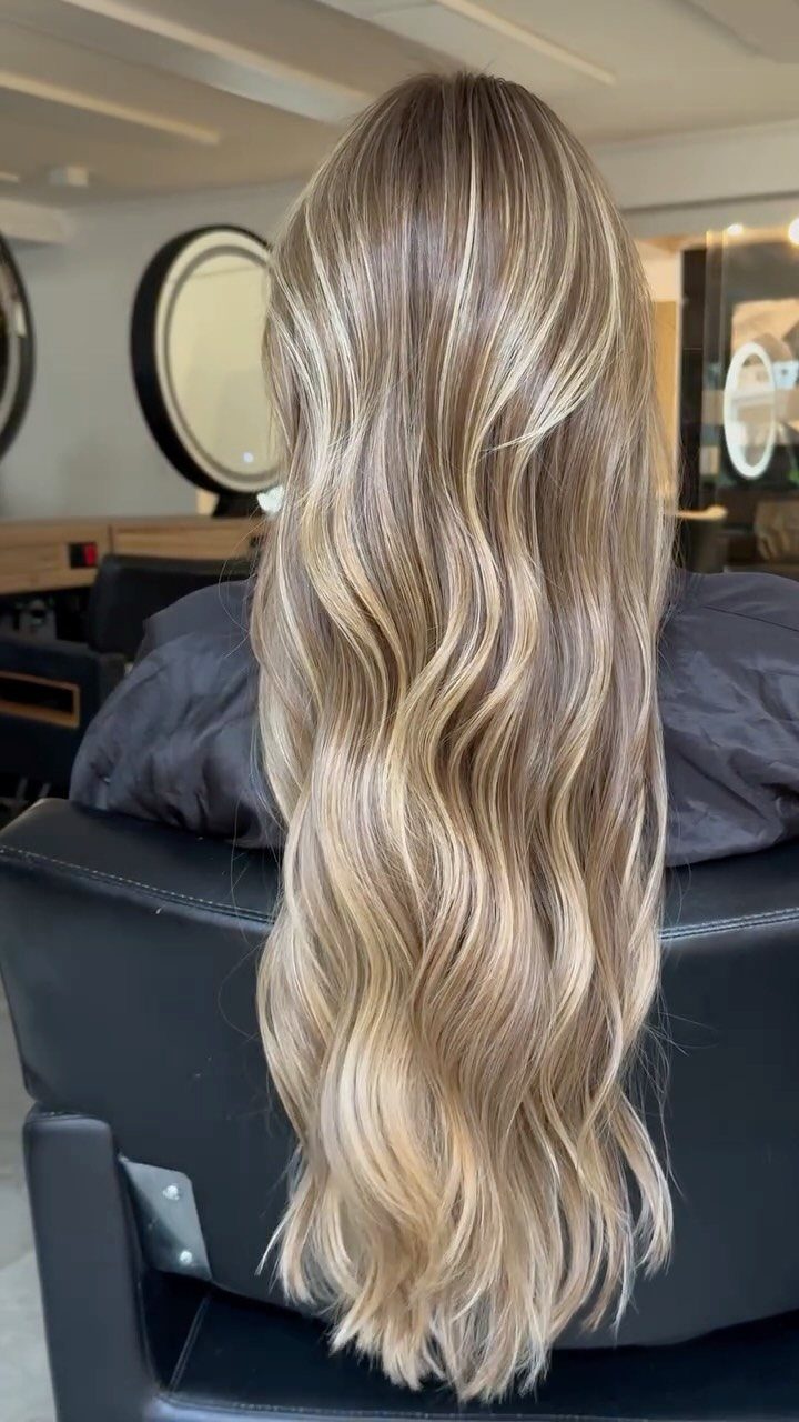 Long wavy blonde hair blends cool ash strands with warm golden highlights