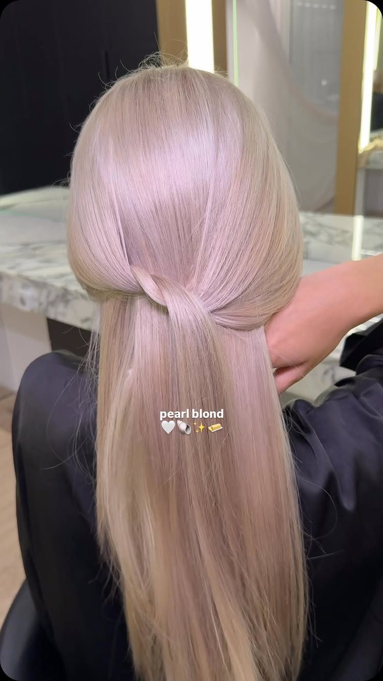 Pearl-blonde hair gathered into a long, smooth low twist in a salon