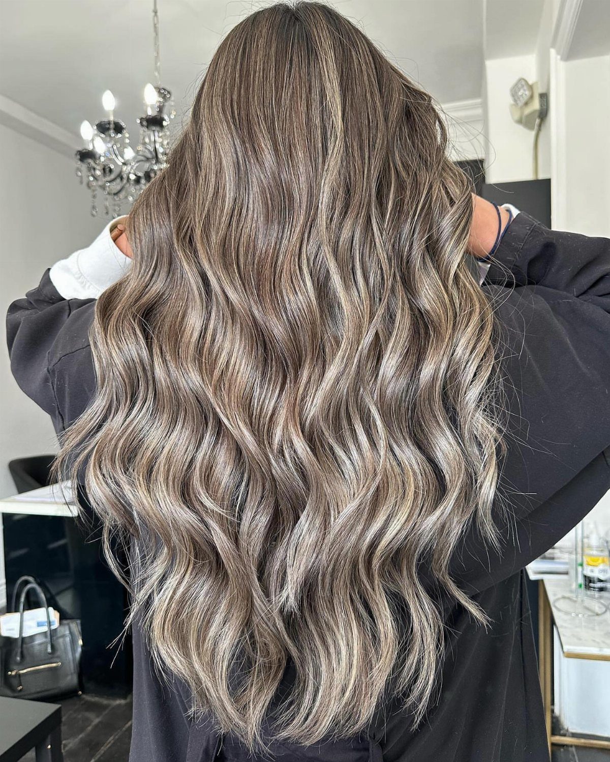 Long wavy smoky ash-blonde hair with dark roots shown from behind