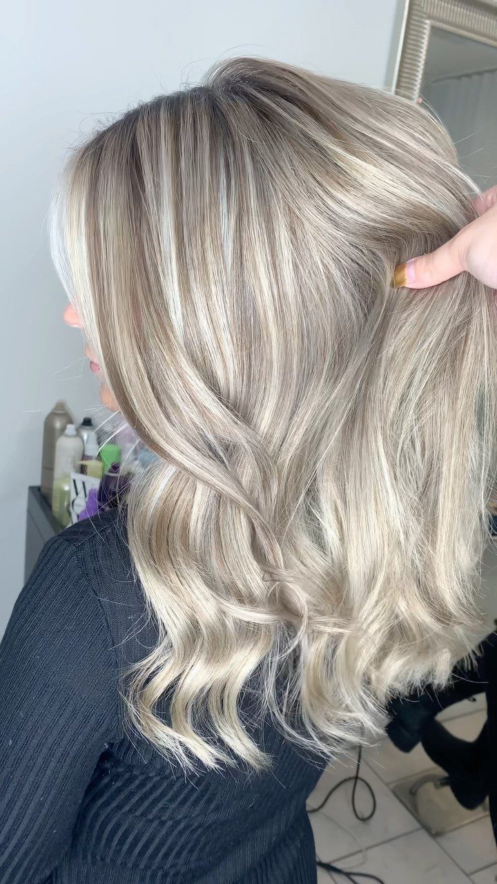 Wavy ash blonde hair with lighter highlights woven through a darker blonde base