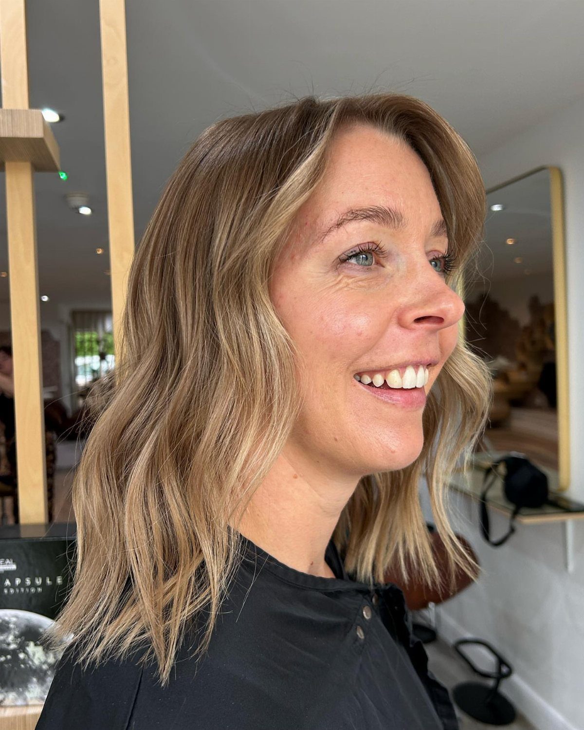 Woman showing shoulder-length dark blonde hair with blended lighter balayage highlights