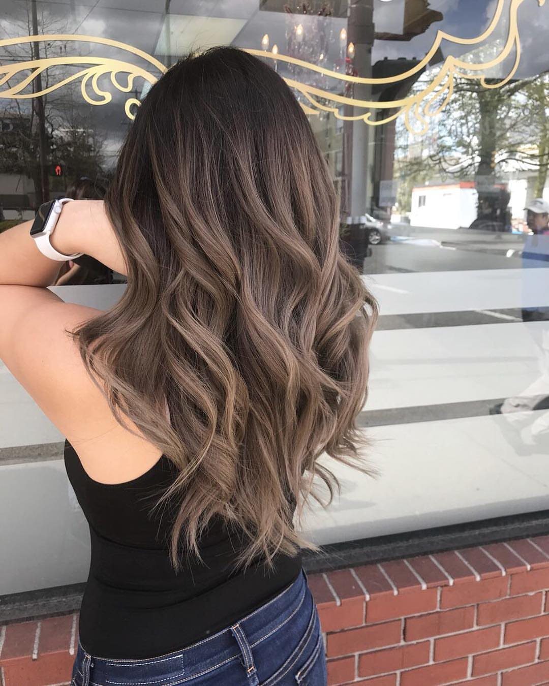 Wavy dark ash blonde hair fades from dark roots to lighter ends