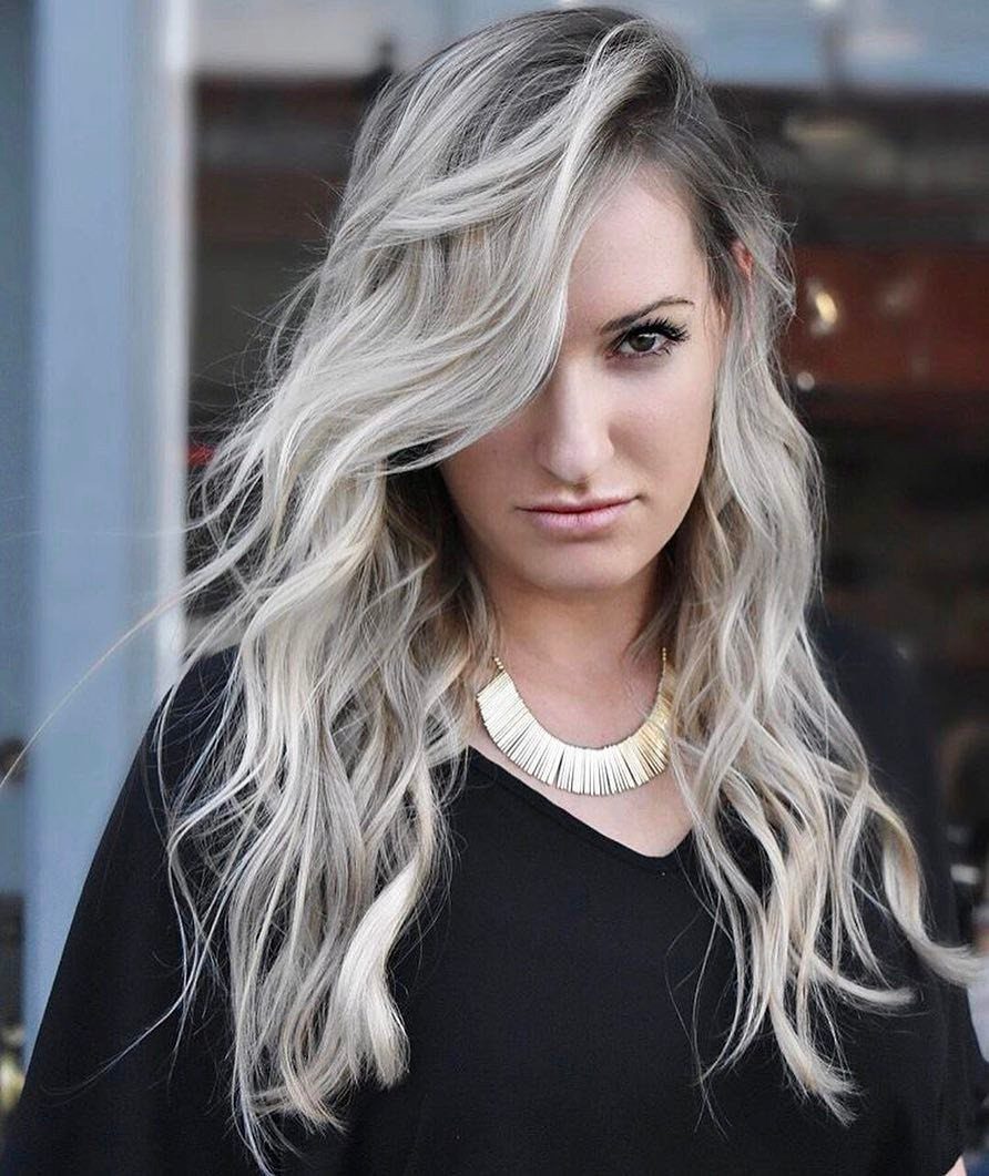 Woman showing long wavy ash blonde hair with darker blended roots
