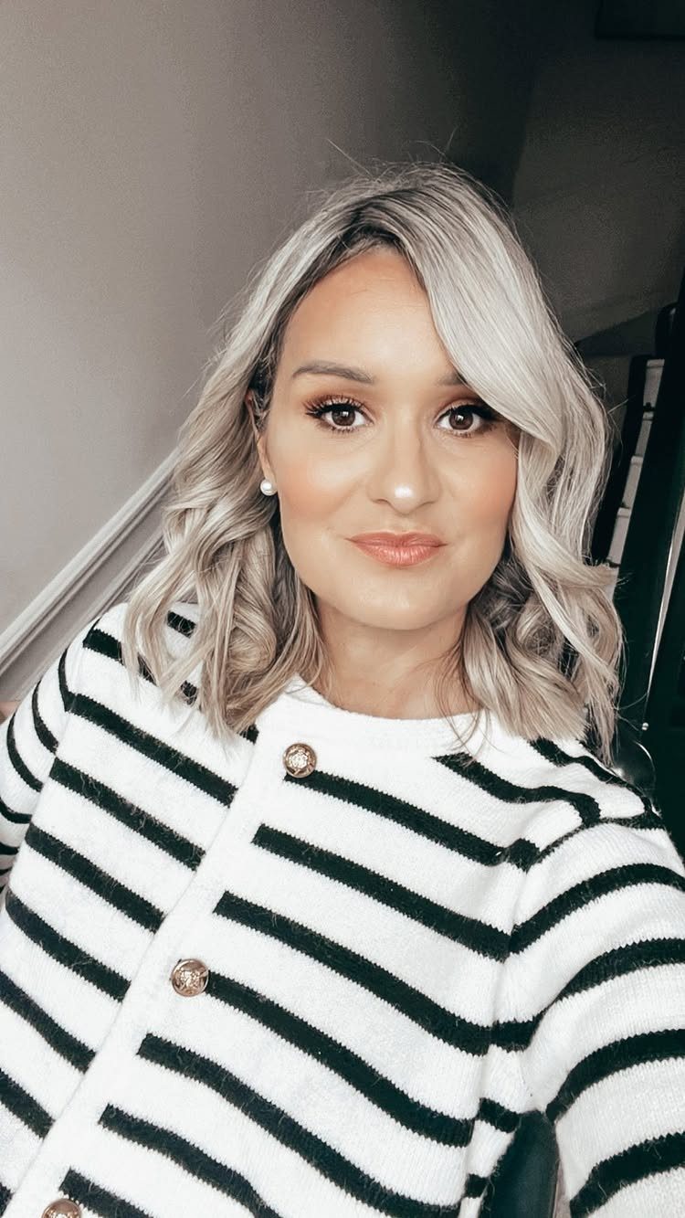 Woman with a beige blonde wavy lob and center part