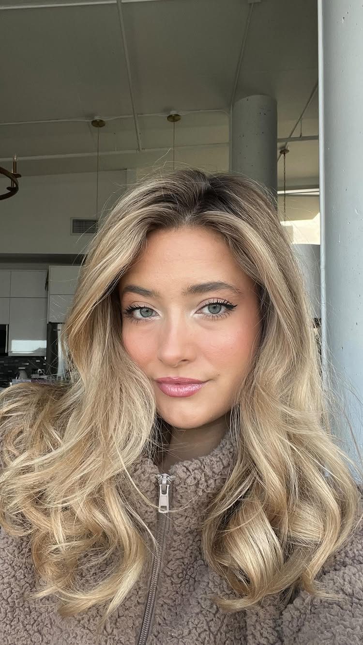 Woman showing long wavy beige blonde hair with dimensional bronde ribbons