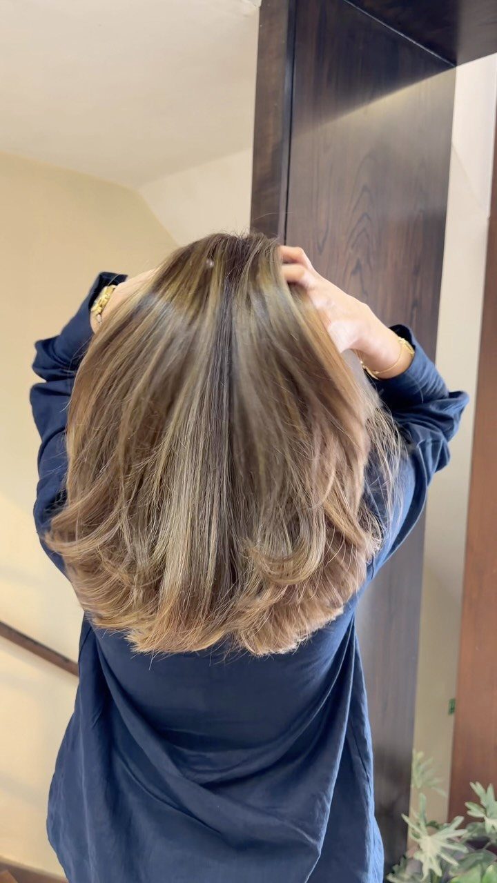 Dark brown hair with beige blonde highlights and softly curled layered ends