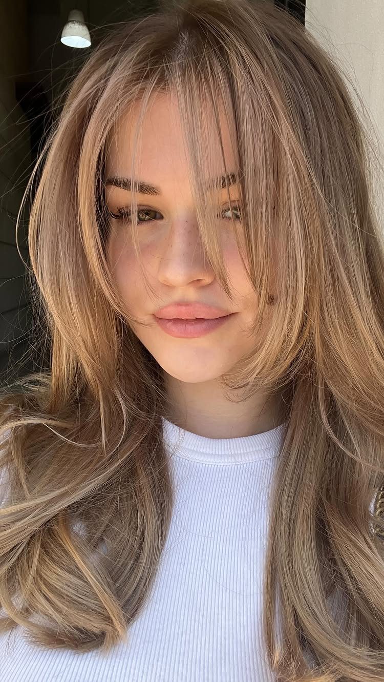 Woman with long beige-blonde layers and lighter face-framing strands