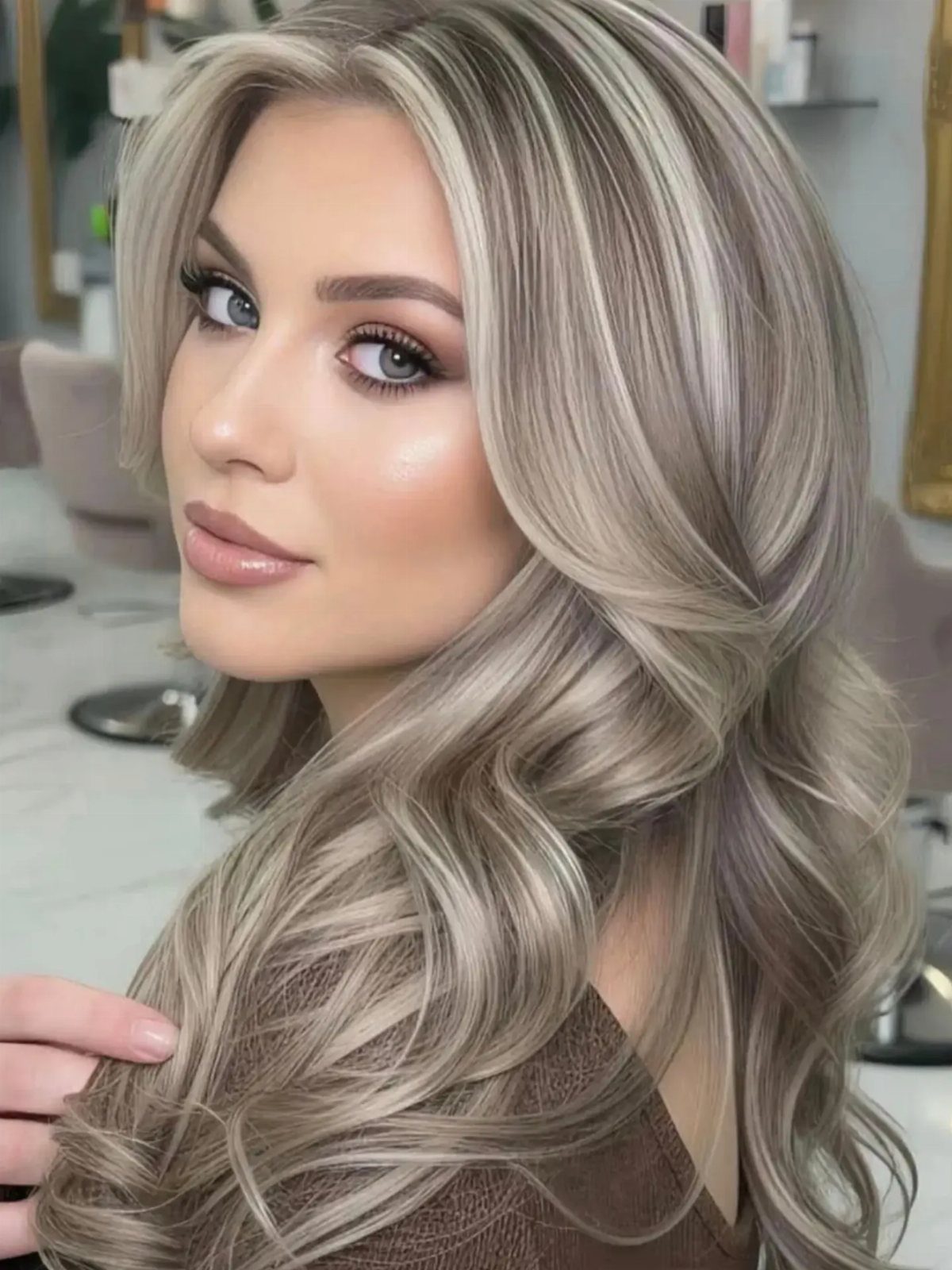 Woman showing long beige-blonde highlighted waves with soft, subtle layers