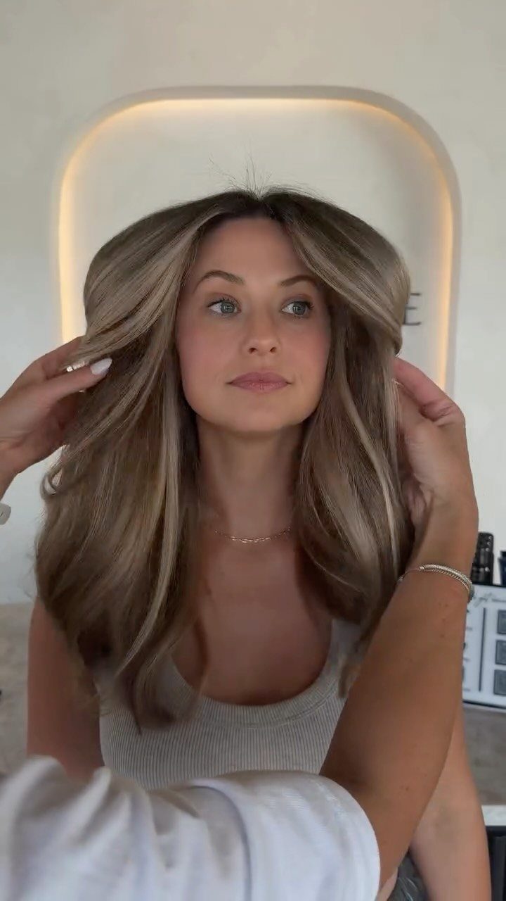 Woman showing long beige blonde hair with darker lowlights and face-framing layers