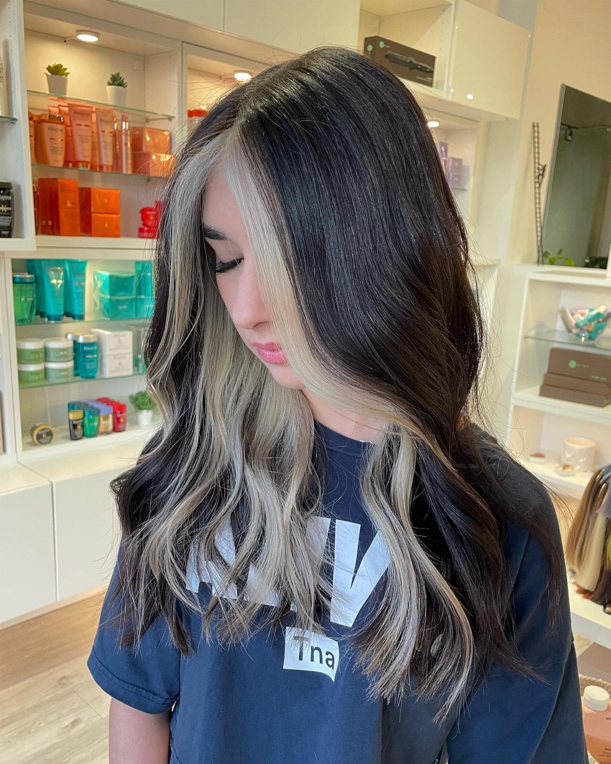 Long dark waves with pale blonde face-framing highlights in a salon