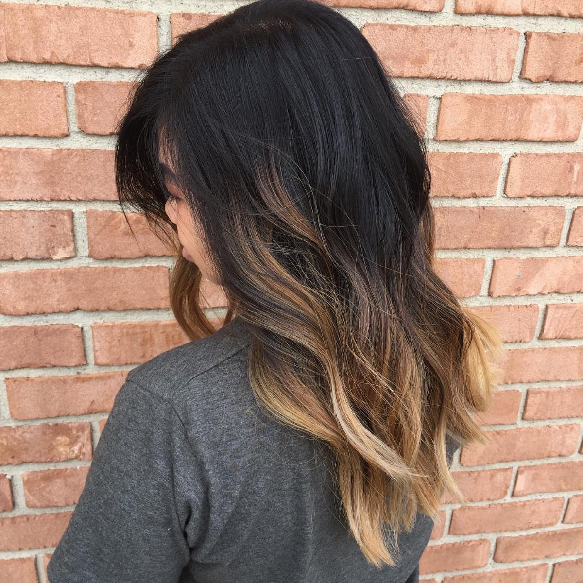 Long wavy black hair gradually lightens to blonde at the ends
