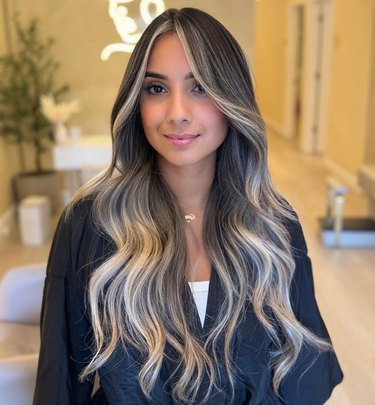 Woman with long dark waves and chunky beige-blonde face-framing highlights