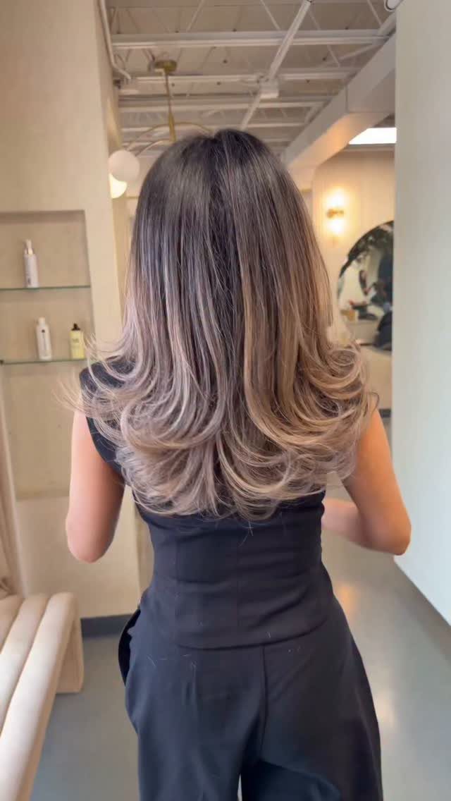 Layered dark brown hair with cool dark blonde highlights and curled ends