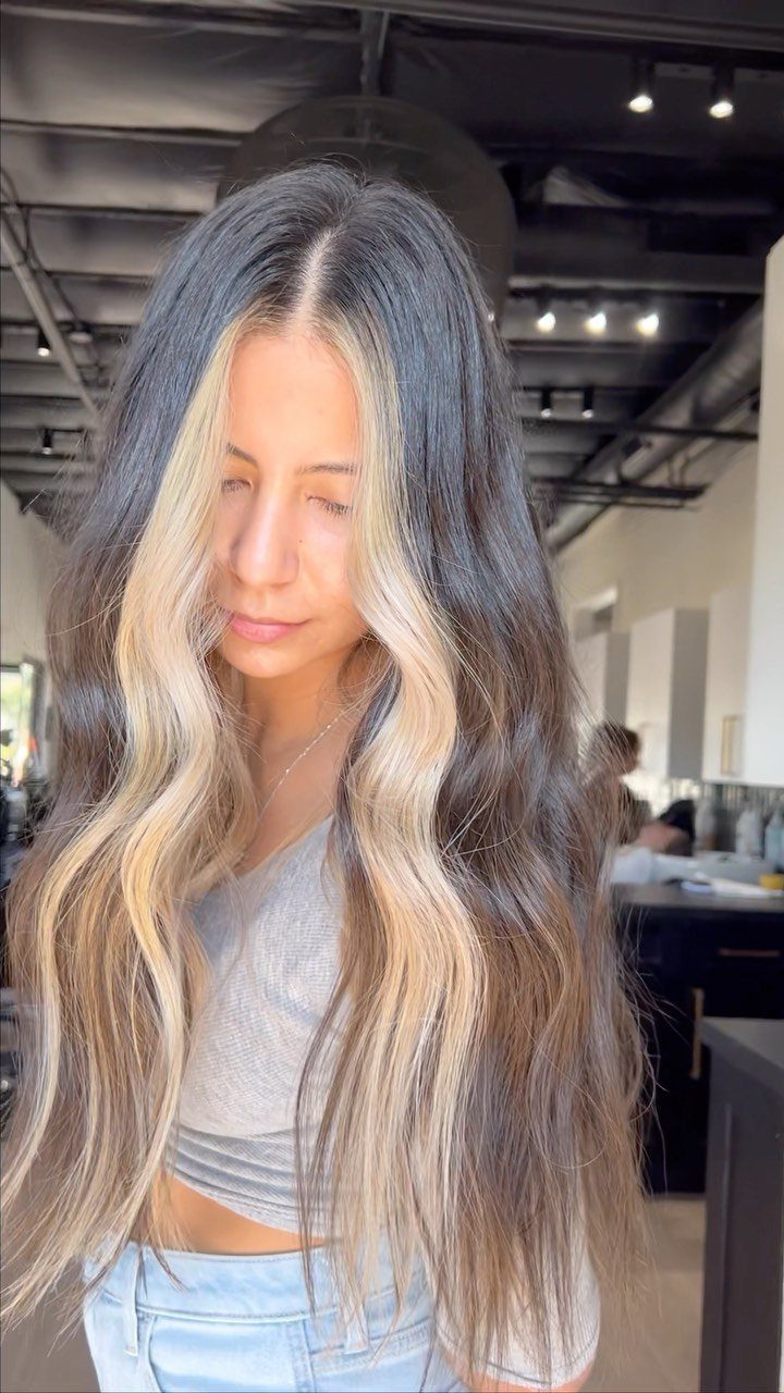 Woman with long dark hair and broad icy blonde face-framing sections
