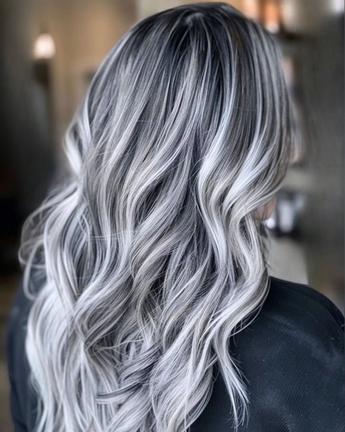 Long wavy black hair with icy platinum highlights cascading down the back