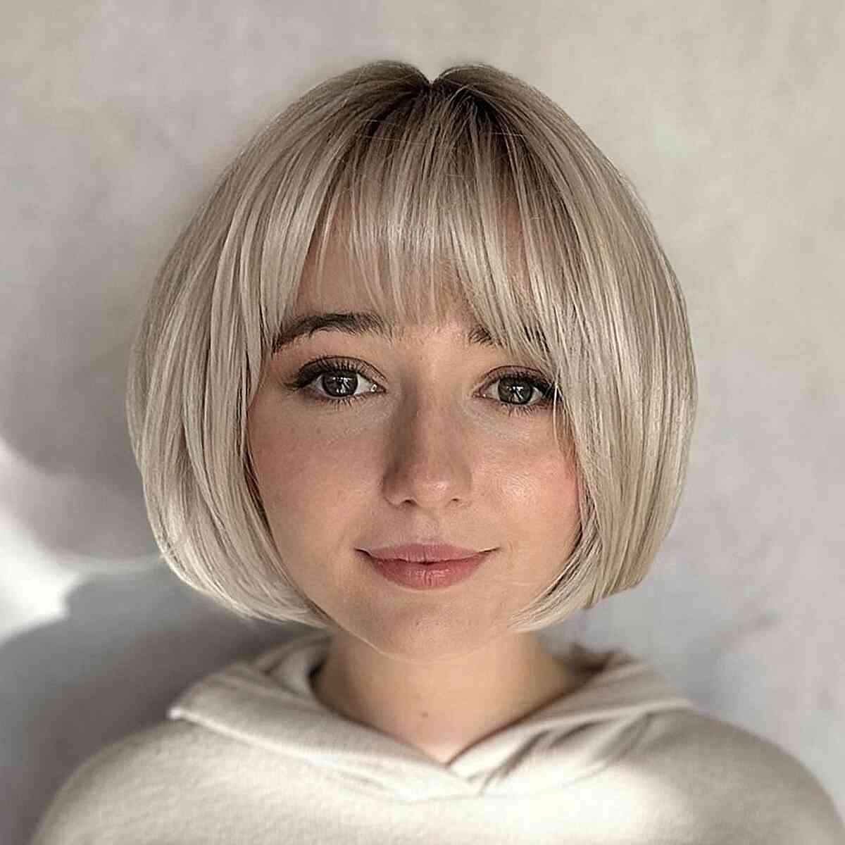 Woman with a short ash-blonde bob and straight blunt bangs