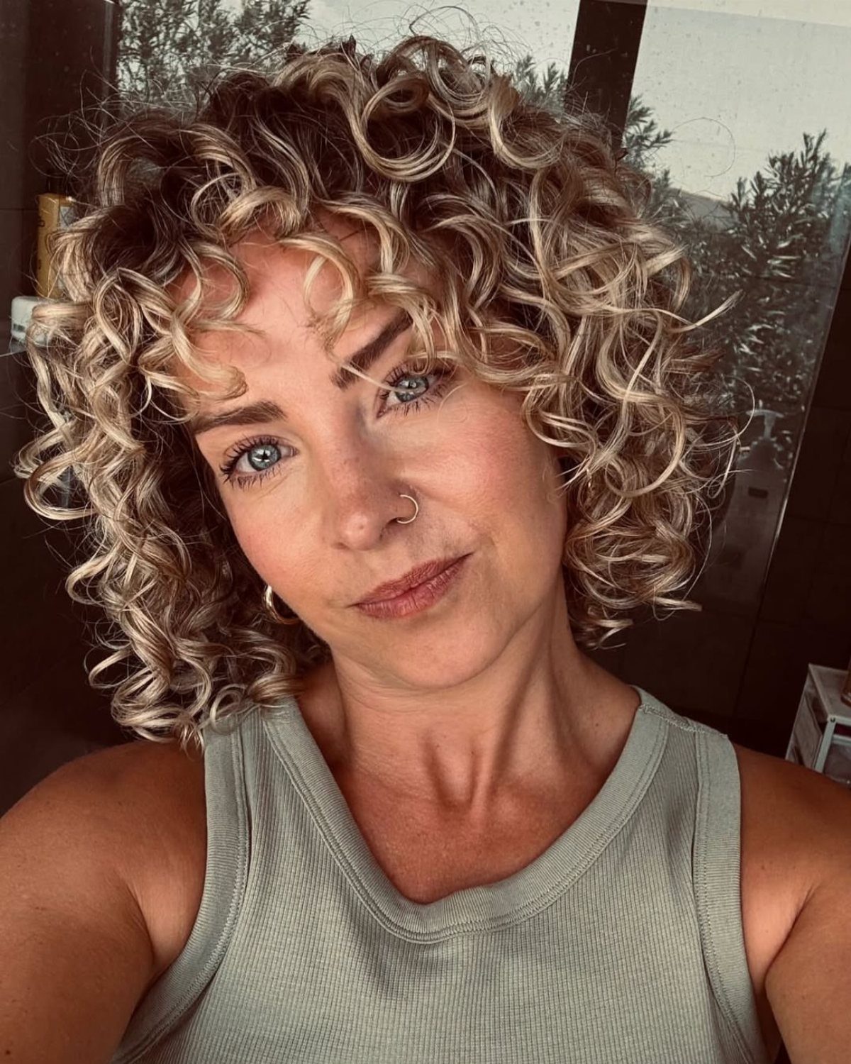 Person with a voluminous curly blonde bob and darker roots