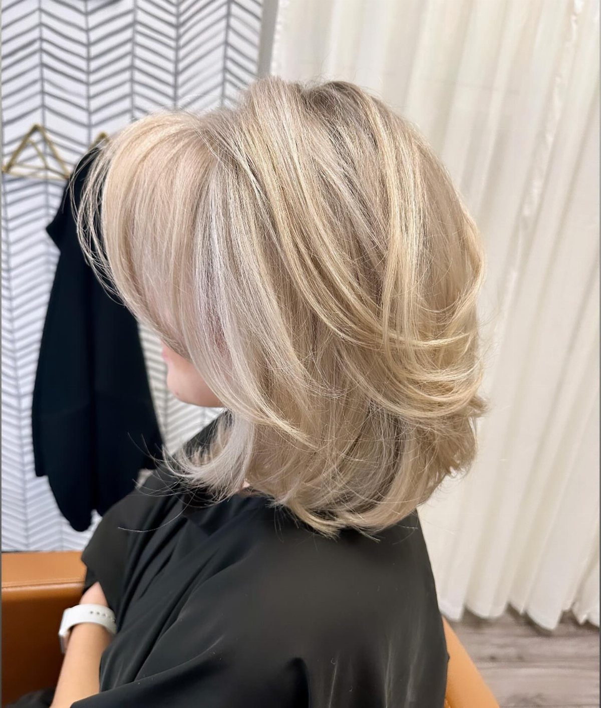 Layered blonde bob with soft, outward-curving ends on a seated woman