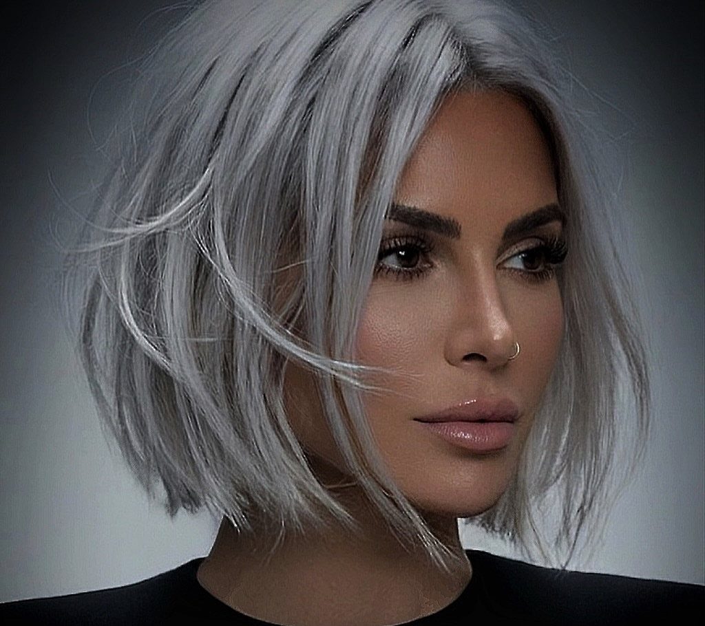 Woman with a textured platinum bob and side part against a gray background