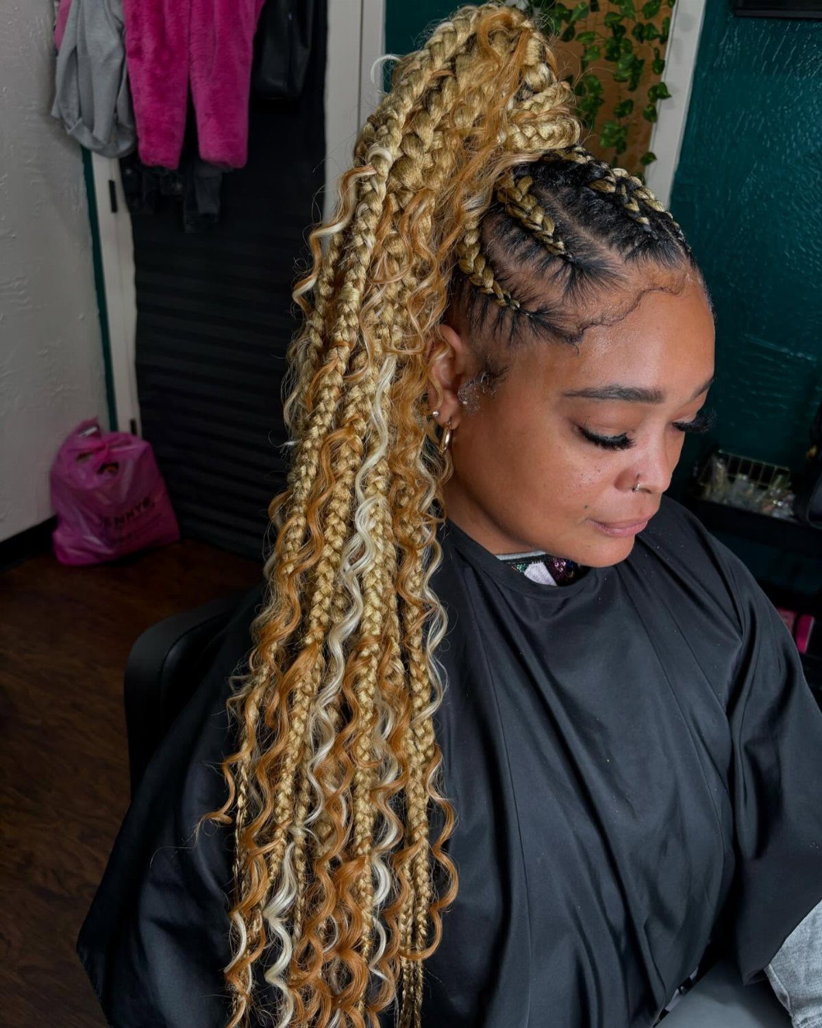 Blonde braided curls gathered high cascade over a woman’s shoulder in a salon