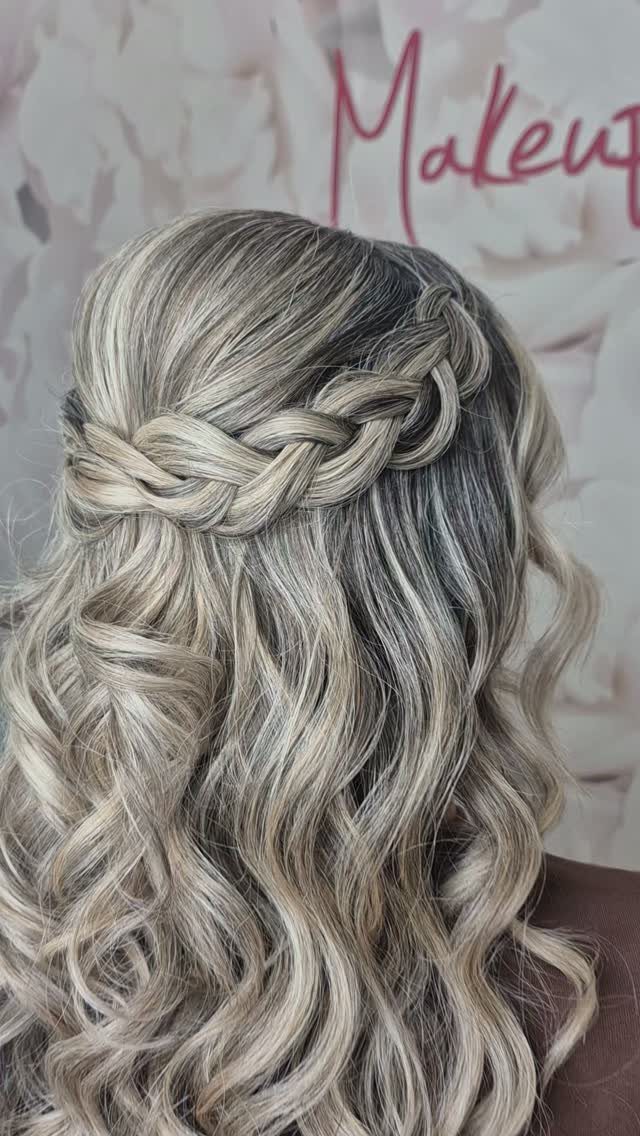 Blonde curls cascade beneath a braided crown hairstyle with dark roots