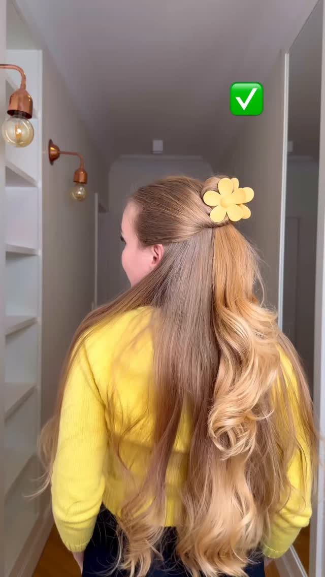 Long blonde waves gathered half-up with a yellow flower-shaped hair clip