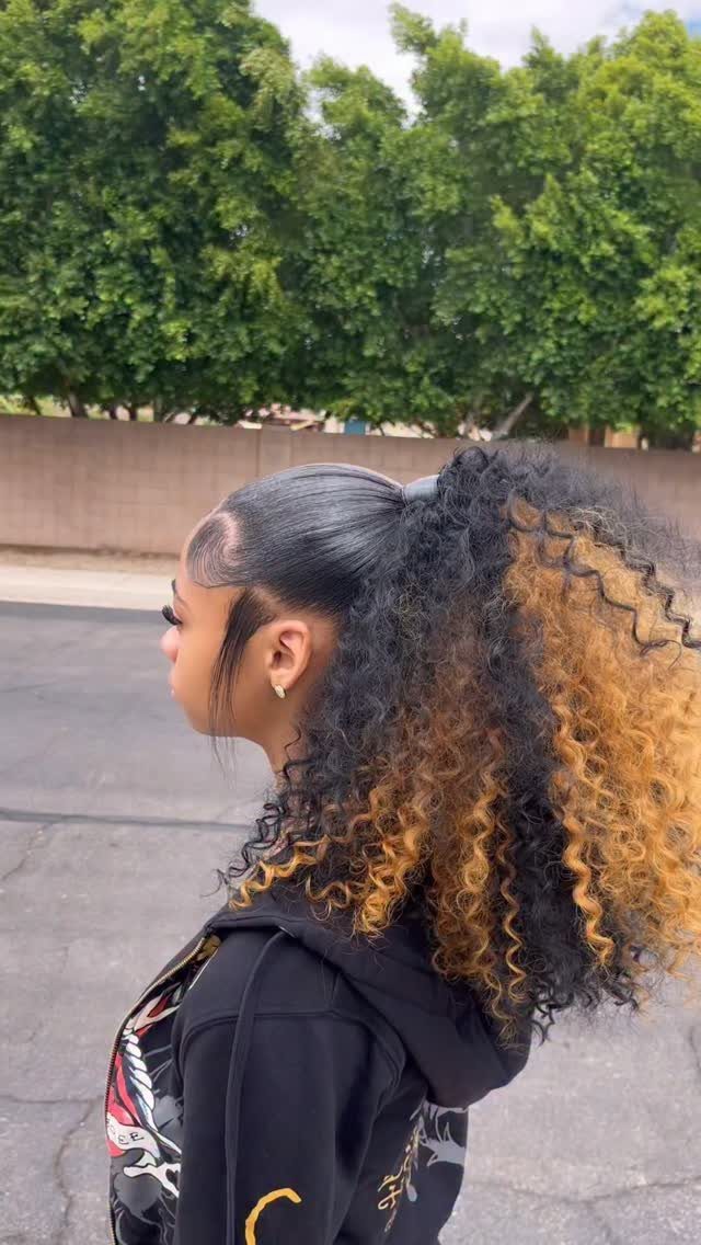 Curly blonde-brown hair with dark roots gathered into a voluminous ponytail