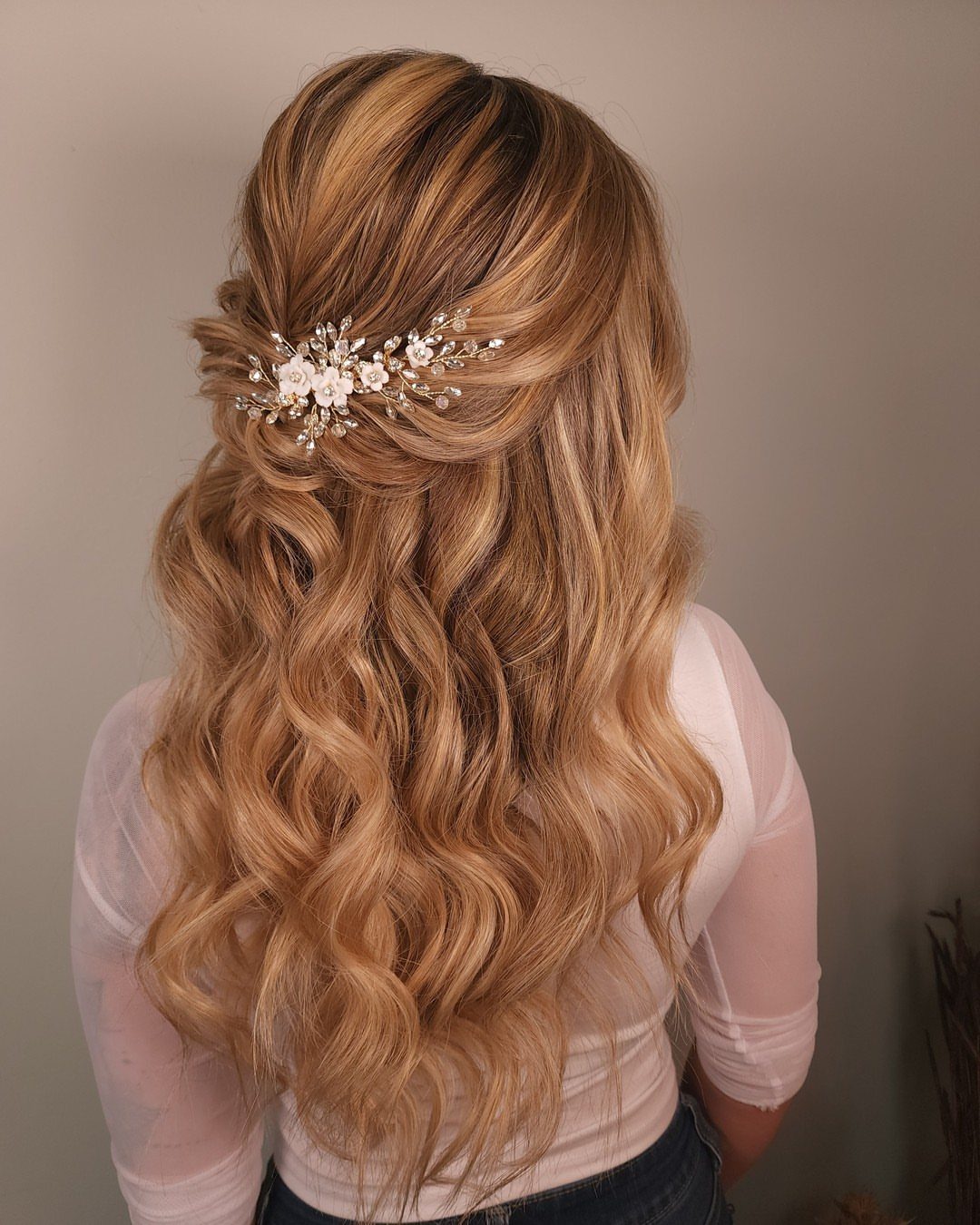 Long blonde curls pinned half-up with a sparkling floral hair accessory
