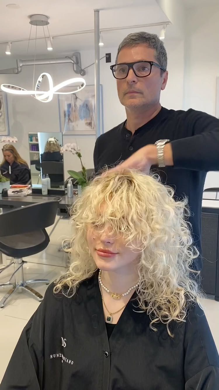 Blonde curly shag with choppy bangs in a salon chair