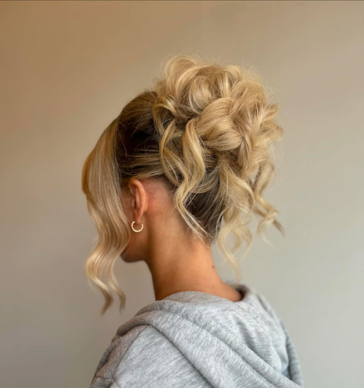 Blonde curly hair arranged in a high loose updo with tendrils