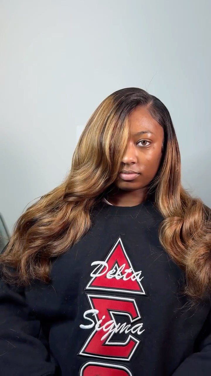 Woman with long highlighted waves and a deep side part wearing a black sweatshirt