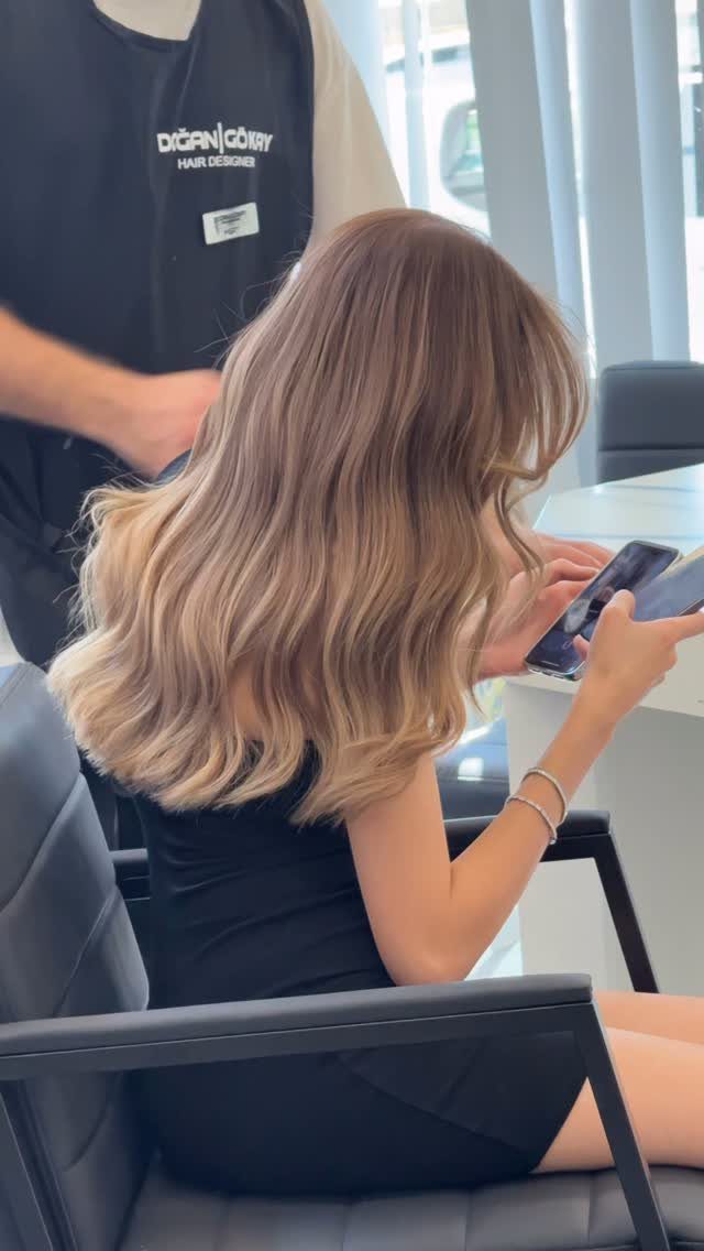 Wavy light brown hair with subtle warm blonde highlights in a salon