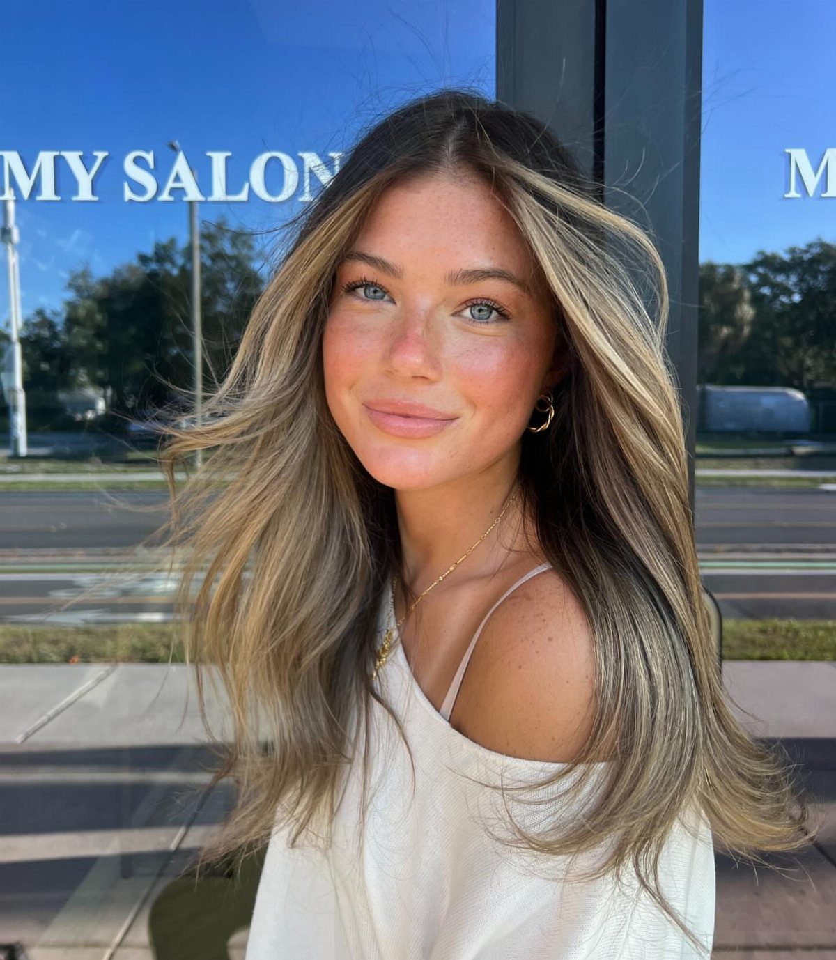 Woman with wavy dark blonde hair and bright face-framing blonde pieces