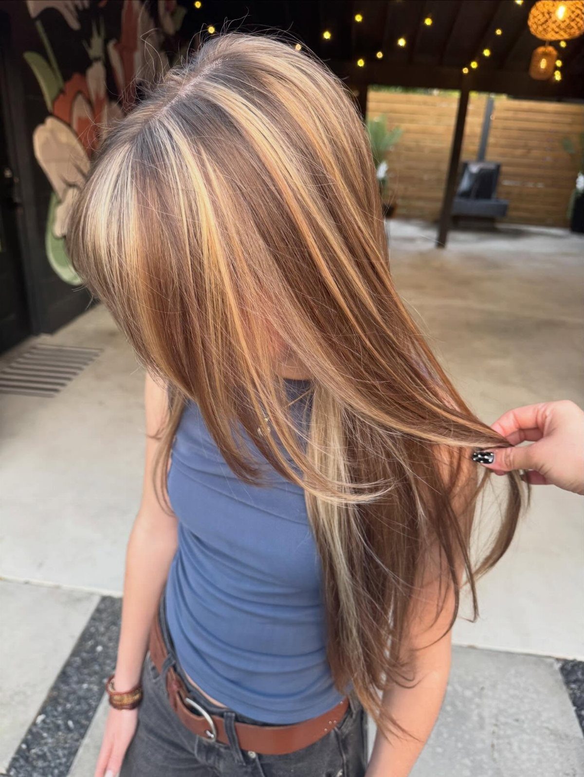 Long brown hair with broad golden-blonde highlights, lifted to show the color contrast