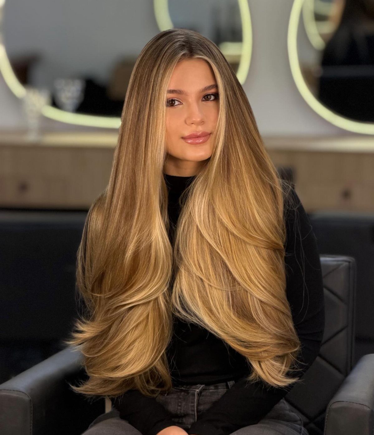 Woman with glossy honey-golden blonde hair styled in long, flowing layers