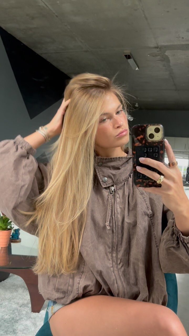 Woman showing long golden blonde balayage hair in a mirror selfie