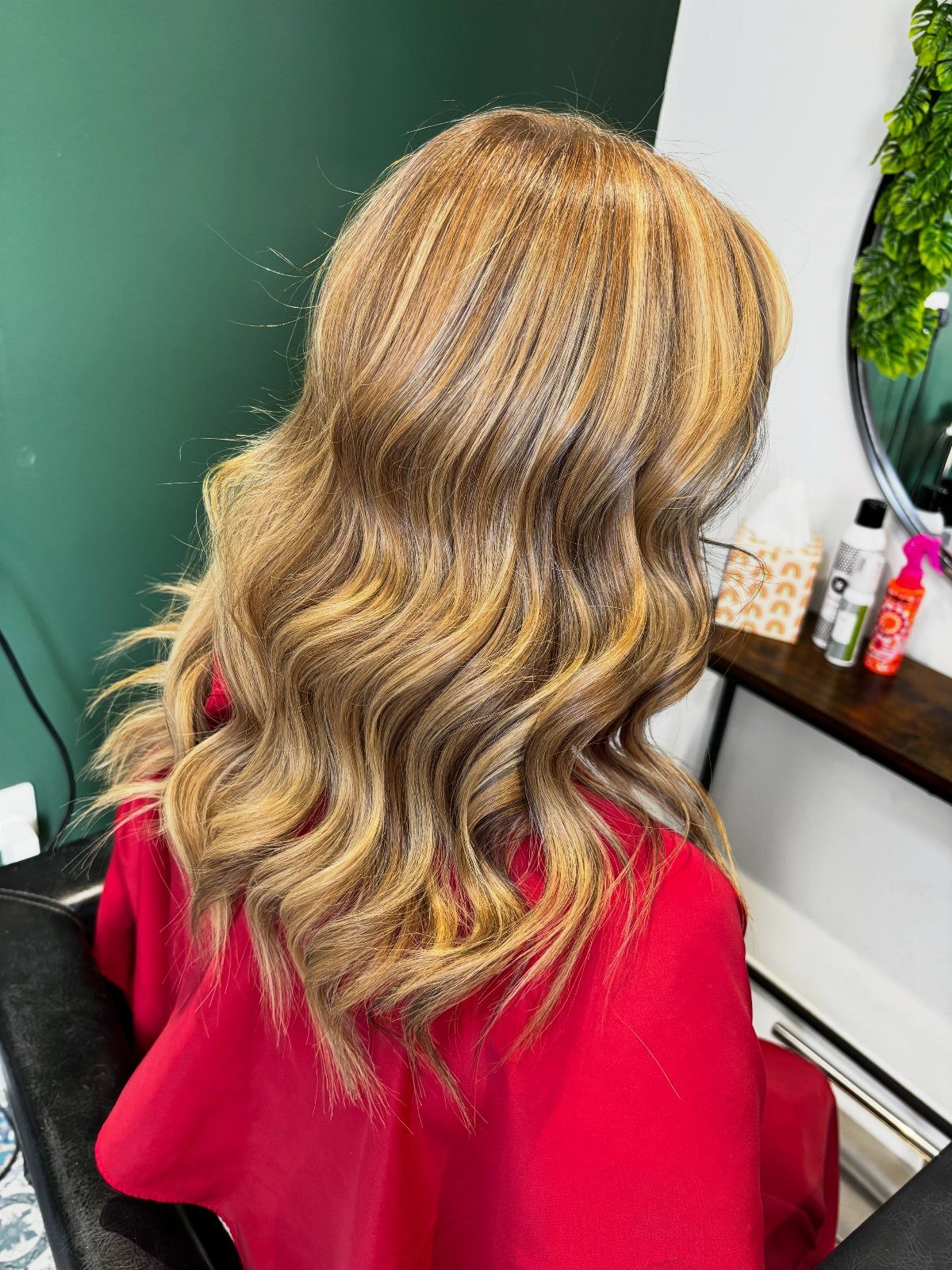 Long wavy light brown hair with caramel and golden highlights in a salon.