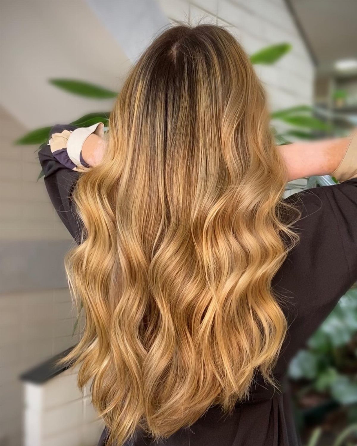 Long wavy hair fades from dark brown roots to golden blonde ends