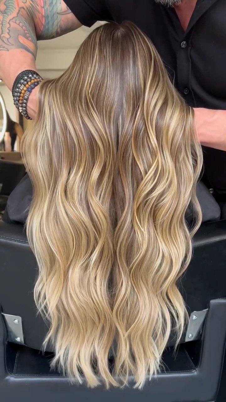 Long wavy golden blonde hair with soft beige highlights and darker roots